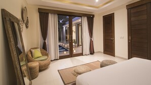 A bedroom with a large bed, a wicker chair, a mirror, and a view of an outdoor pool area. - Marijo Villa 2BR Private Pool Mins to Central Ubud (Ubud)