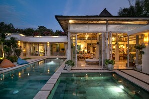 Um resort moderno com piscina, área de estar externa e espaço coberto com vista para a piscina.