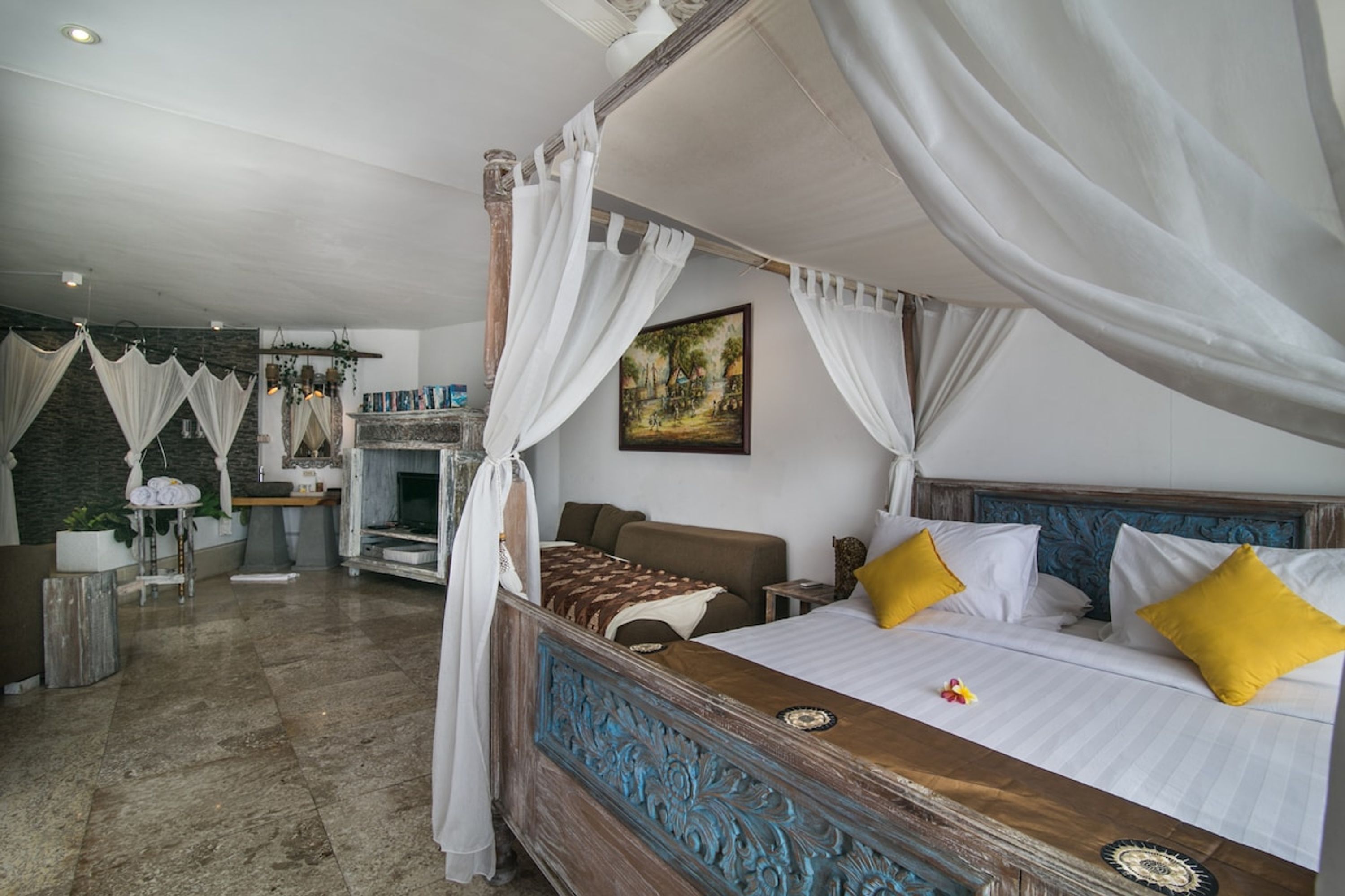 A four-poster bed with white and yellow pillows, a wooden headboard, and a canopy.