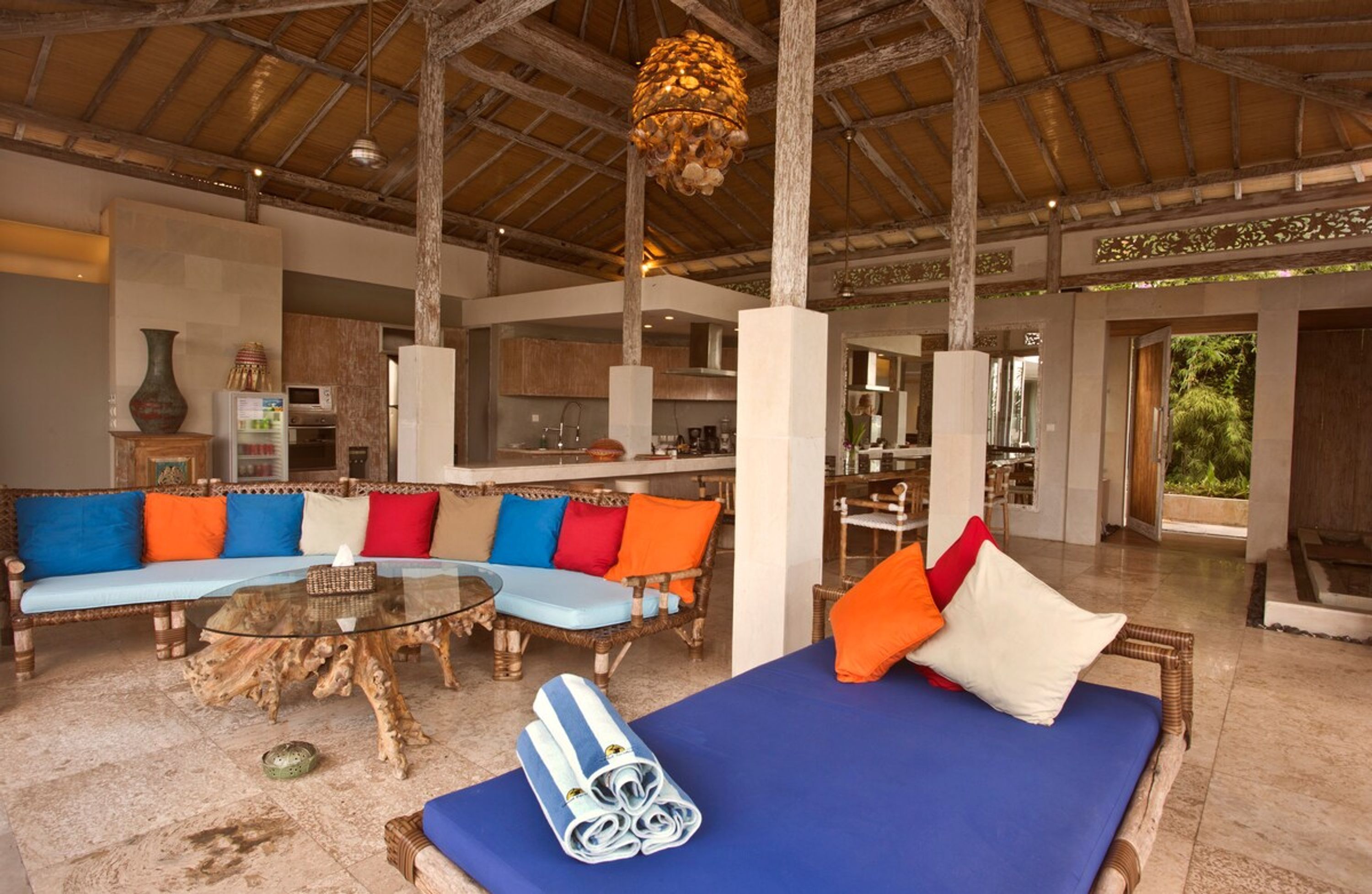 A spacious living area with a large sofa set, a dining table, and a lounge area with a blue sofa and a bed.