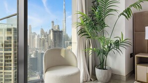 Ein modernes Wohnzimmer mit einem großen Fenster und Blick auf eine Stadtlandschaft, darunter ein markanter Wolkenkratzer.