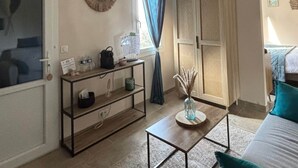 A room with a bed, a desk with a lamp, a window with curtains, and a wall-mounted shelf. - Grenache room (La Garde-Adhémar)