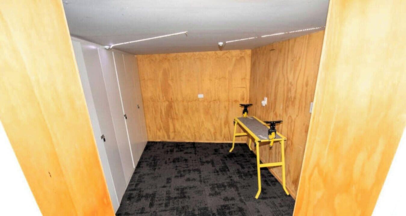 Ein Zimmer mit einer Holzwand, einem schwarzen Teppich und einem gelben Tisch mit schwarzer Tischplatte.