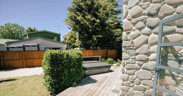 A wooden deck with a stone wall, a wooden fence, and a green lawn. - Spacious Mt Hutt Ski & Summer Lodge in Methven with Spa (Methven)