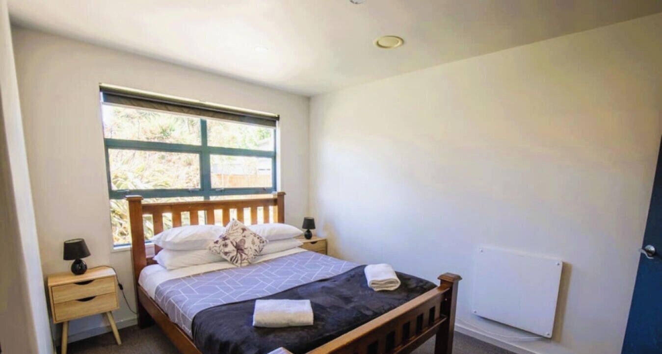 A bedroom with a single bed, a nightstand, a window, and a radiator.