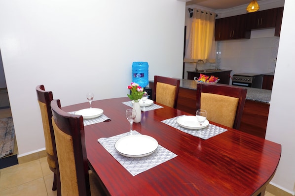 A dining table set with plates, glasses, and a vase of flowers.