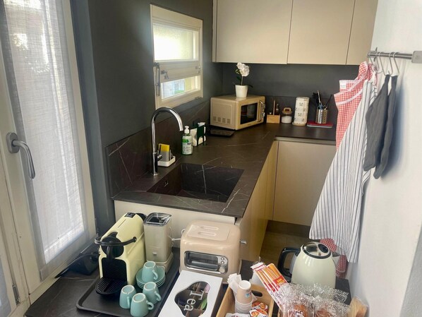 A compact kitchen with a sink, microwave, toaster, and a small dining area with a table and chairs.