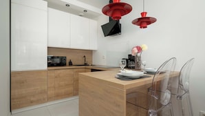 Una cocina moderna con armarios de madera, una isla central y un comedor con sillas transparentes.