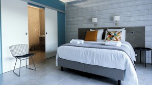 Une chambre d’hôtel moderne avec un grand lit, une chaise et une armoire.