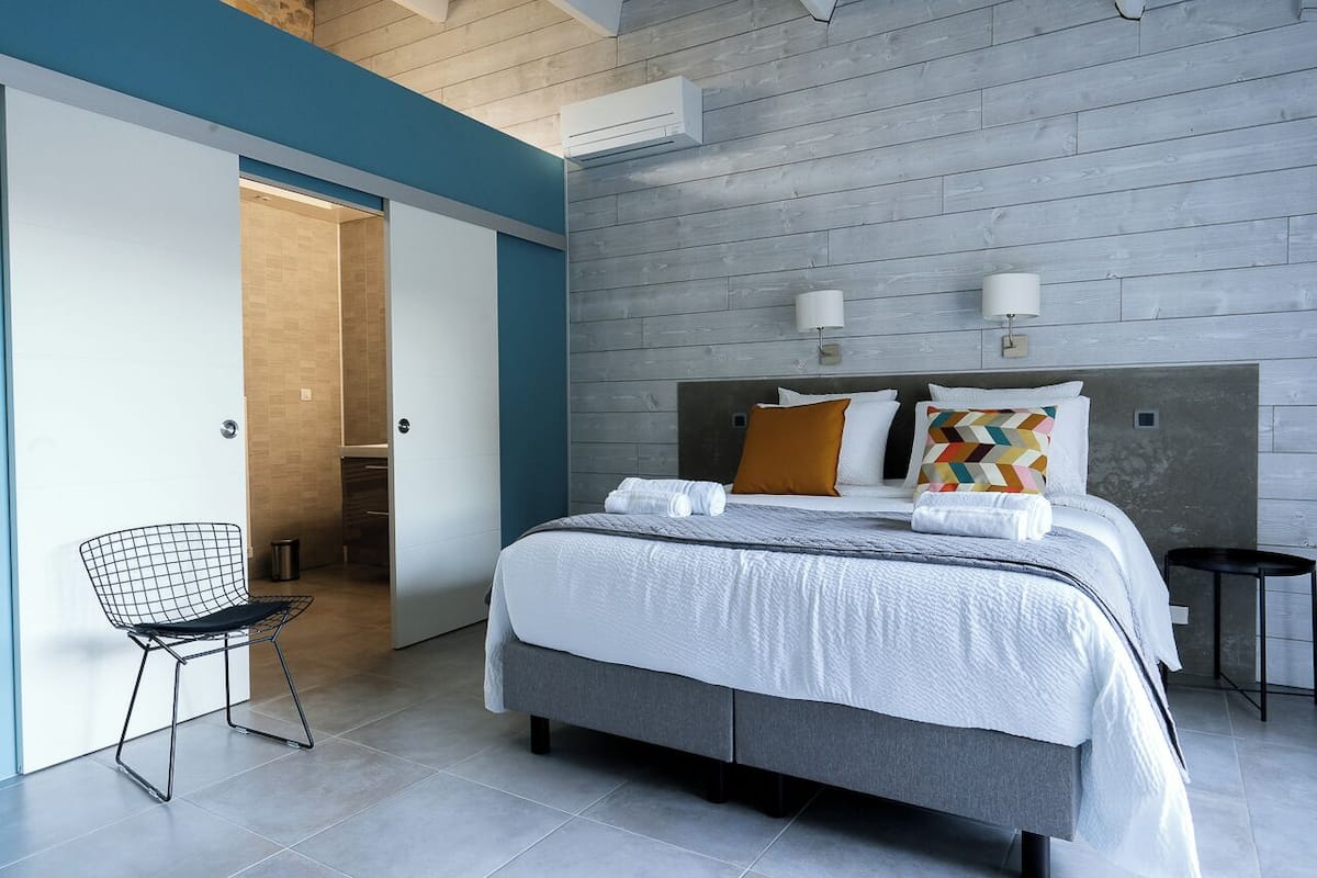 Een moderne hotelkamer met een groot bed, een stoel en een garderobe.