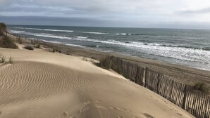 Une plage avec des dunes de sable et une clôture en bois.
