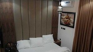 Une chambre à coucher moderne avec un grand lit, un luminaire suspendu et un tableau encadré au mur.