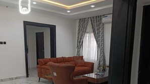 A modern living room with a sectional sofa, a coffee table, and a dining area. - Dwellux Apartments  (Abuja)
