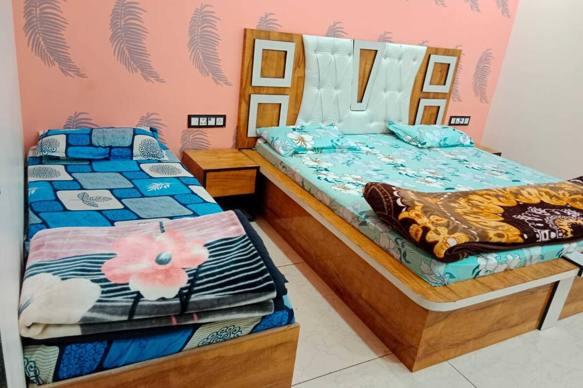 A room with two beds, one with a floral bedspread and the other with a geometric pattern.