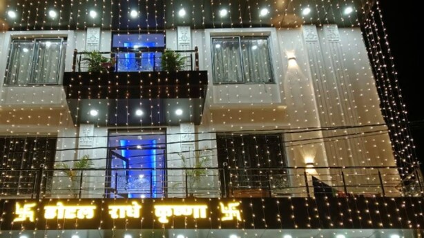 A multi-story building with balconies, string lights, and a neon sign. - Hotel Radhe Krishna (Khatoo)