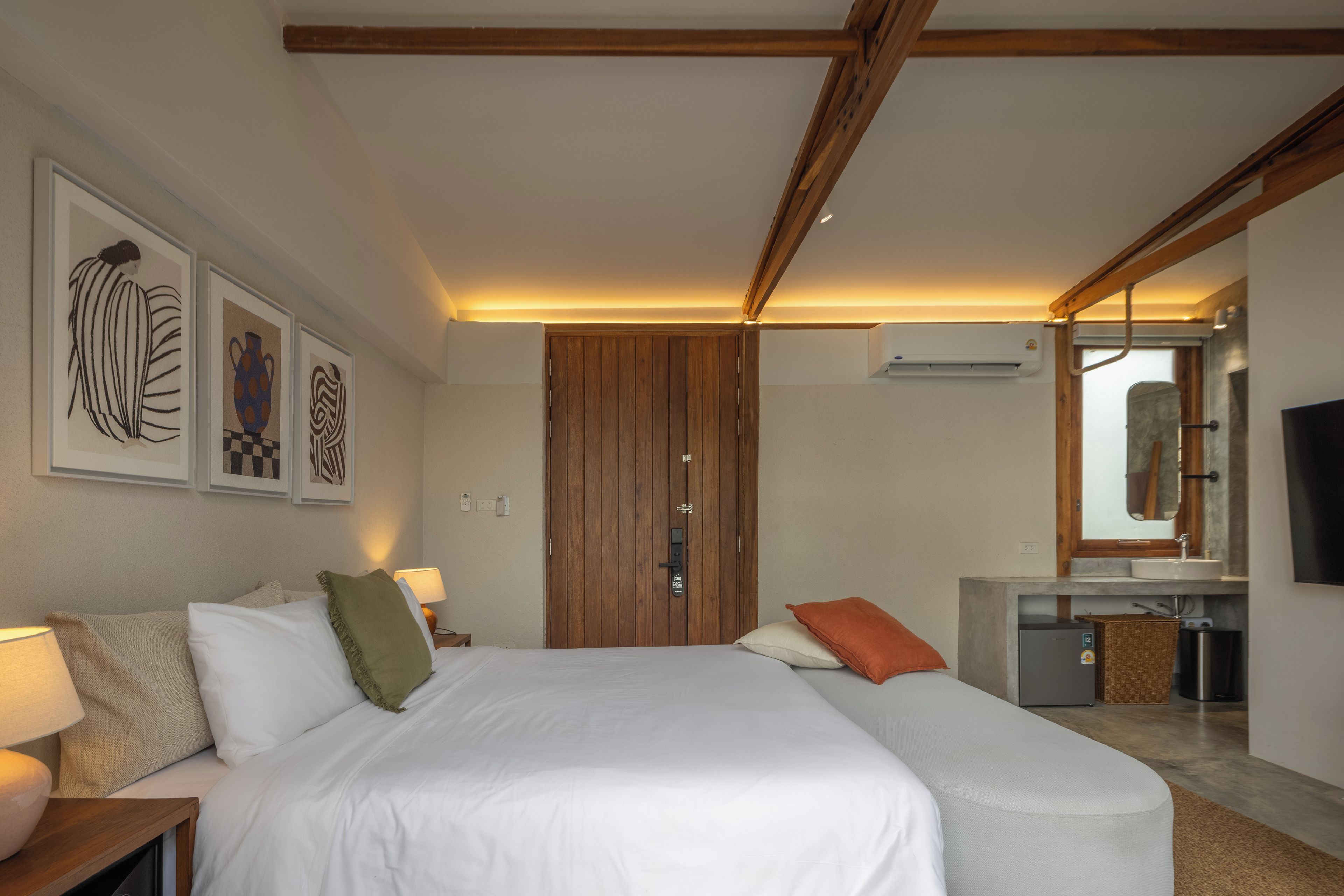 A hotel room with a bed, bedside tables, a mirror, and artwork on the wall.