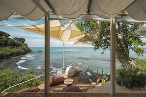 A seaside terrace with a view of the ocean, featuring a seating area with cushions and a table. - Pebble Lanta - Seaview Stay (Ko Lanta)