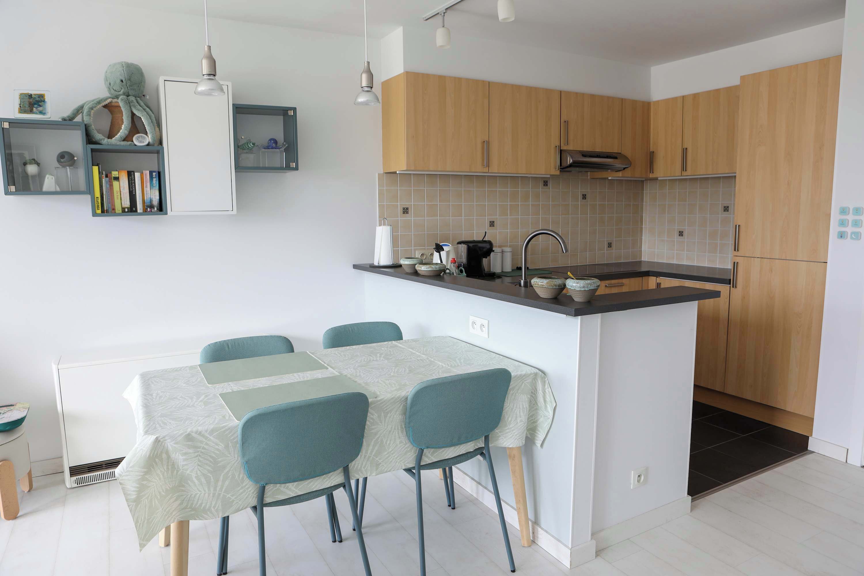 Una cocina moderna con armarios de madera, una isla integrada con pileta y un comedor con mesa y sillas.