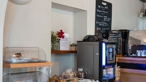 Ein reichhaltiges Frühstücksbuffet mit einer Kaffeemaschine, einer Selbstbedienungsstation und verschiedenen Speisen.