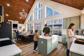 Una cucina moderna con soffitti alti, ampie finestre e un'isola centrale.