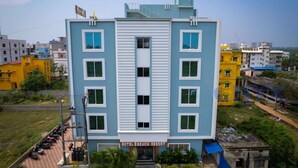 A multi-story hotel with a central entrance, balconies, and a sign indicating it is a hotel beach resort. - New Beach Resort (Brahmagiri)