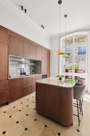 Een moderne keuken met houten kasten, een marmeren aanrechtblad en een centraal eiland.