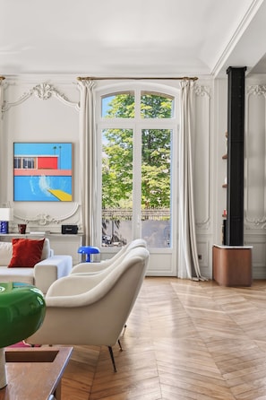 Een woonkamer met een groot raam, een televisie en een bank.
