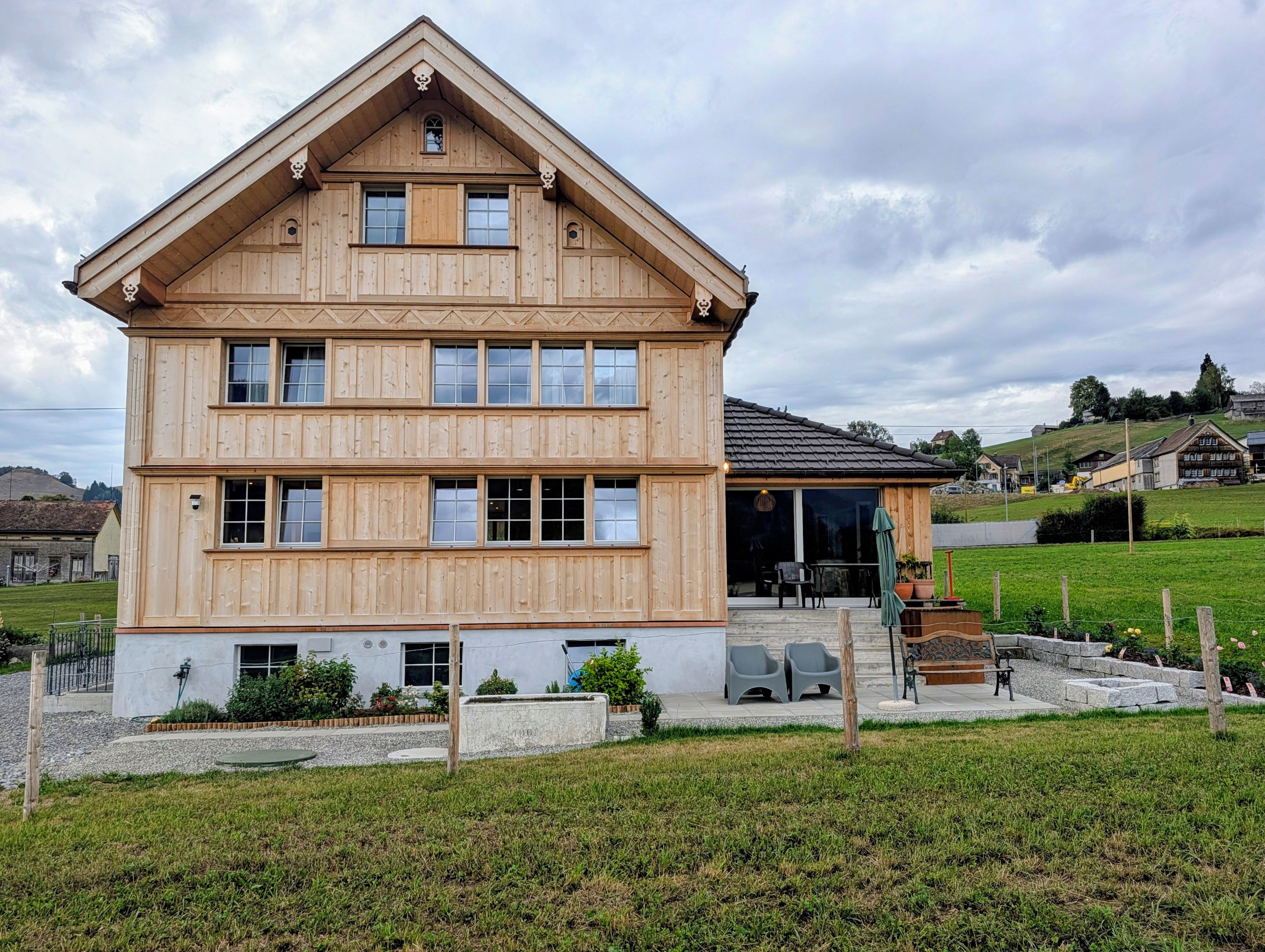 Una casa a più piani in legno con un portico coperto.