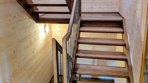 A wooden staircase with a metal railing, leading to a higher floor.