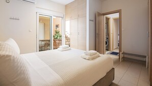 Quarto com cama, guarda-roupa e banheiro visível por uma porta aberta.