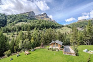 A wooden cabin with a sloped roof, surrounded by a well-maintained lawn and a wooden fence. - Roccia Nera Luxuty Suite Champoluc Monterosa Ski (Ayas)