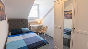 Una camera da letto con un letto, una scrivania, una sedia e un armadio.