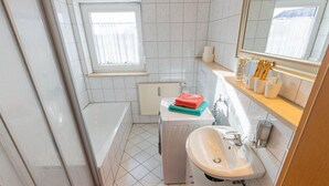 Un bagno con una vasca, un lavandino e una finestra.