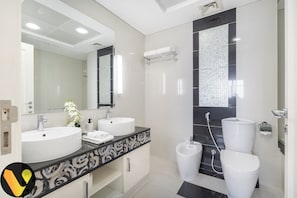 Et moderne badeværelse med to håndvaske, et bidet og et toilet.