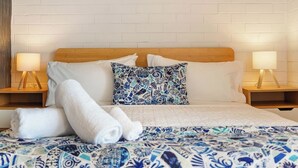 A neatly made bed with a patterned bedspread, two pillows, and two bedside lamps on wooden nightstands. - River Vistas - Fremantle Port Views (North Fremantle)