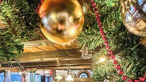 Interior acogedor de un restaurante con mesas y sillas de madera, piso de ladrillo y un árbol de Navidad decorado.