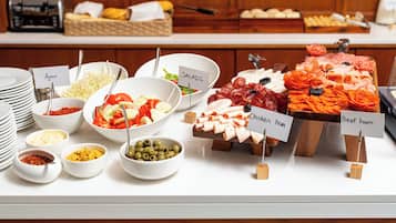 Un bufé con diversas opciones de comida, incluyendo ensaladas, jamón de pollo y jamón de res.