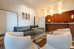 Ett modernt hotellrum med en soffa, fåtöljer, ett soffbord och en receptionsdisk.