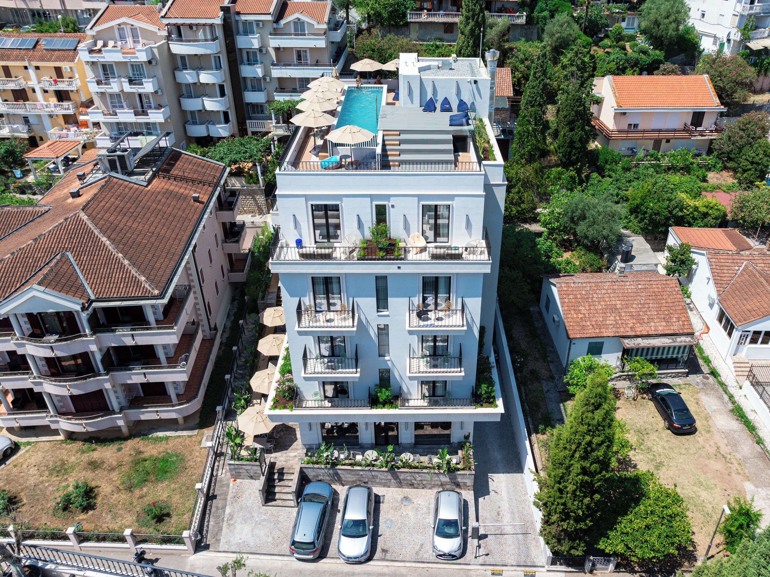 Un edificio residencial de varios pisos con piscina en la azotea, balcones y un estacionamiento.