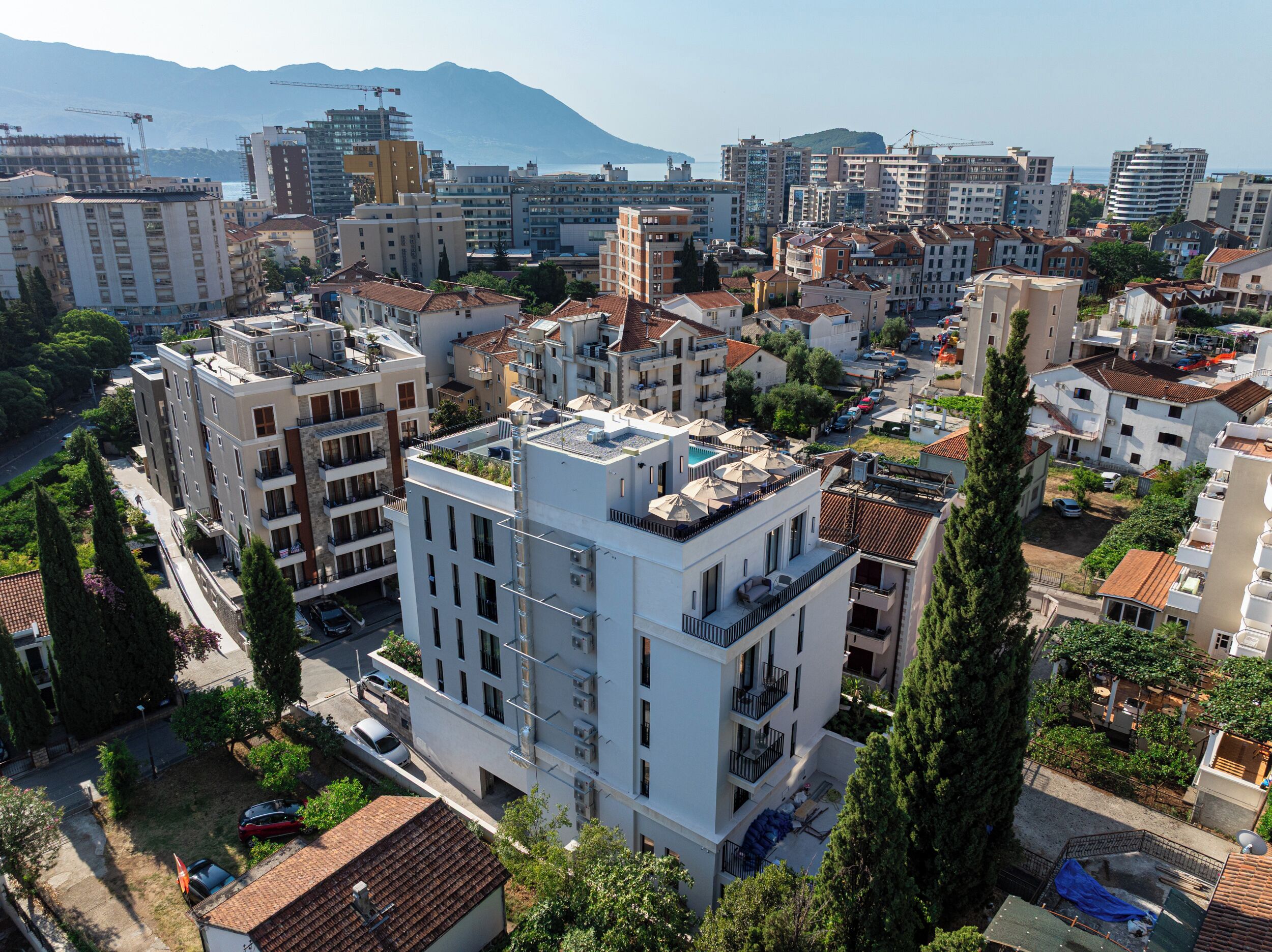 A high-rise residential building with multiple balconies, surrounded by other buildings and greenery.