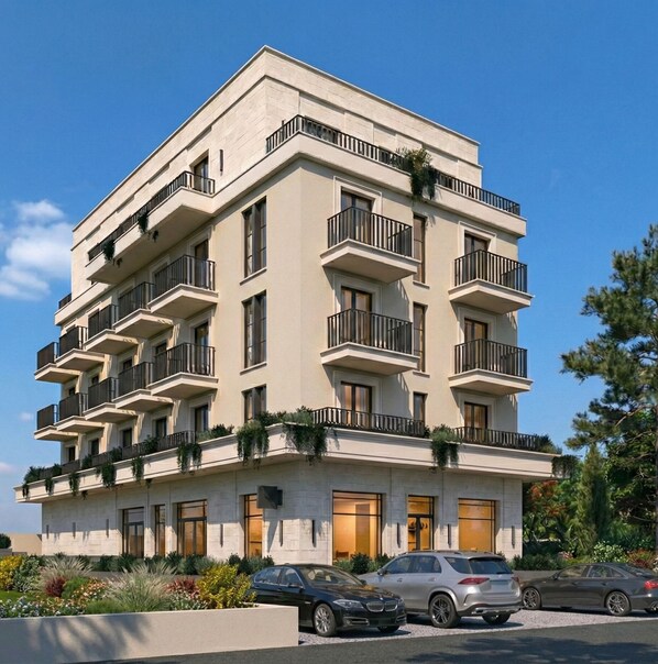 A multi-story building with balconies, a parking area, and a landscaped garden. - Hotel Madeira (Budva)