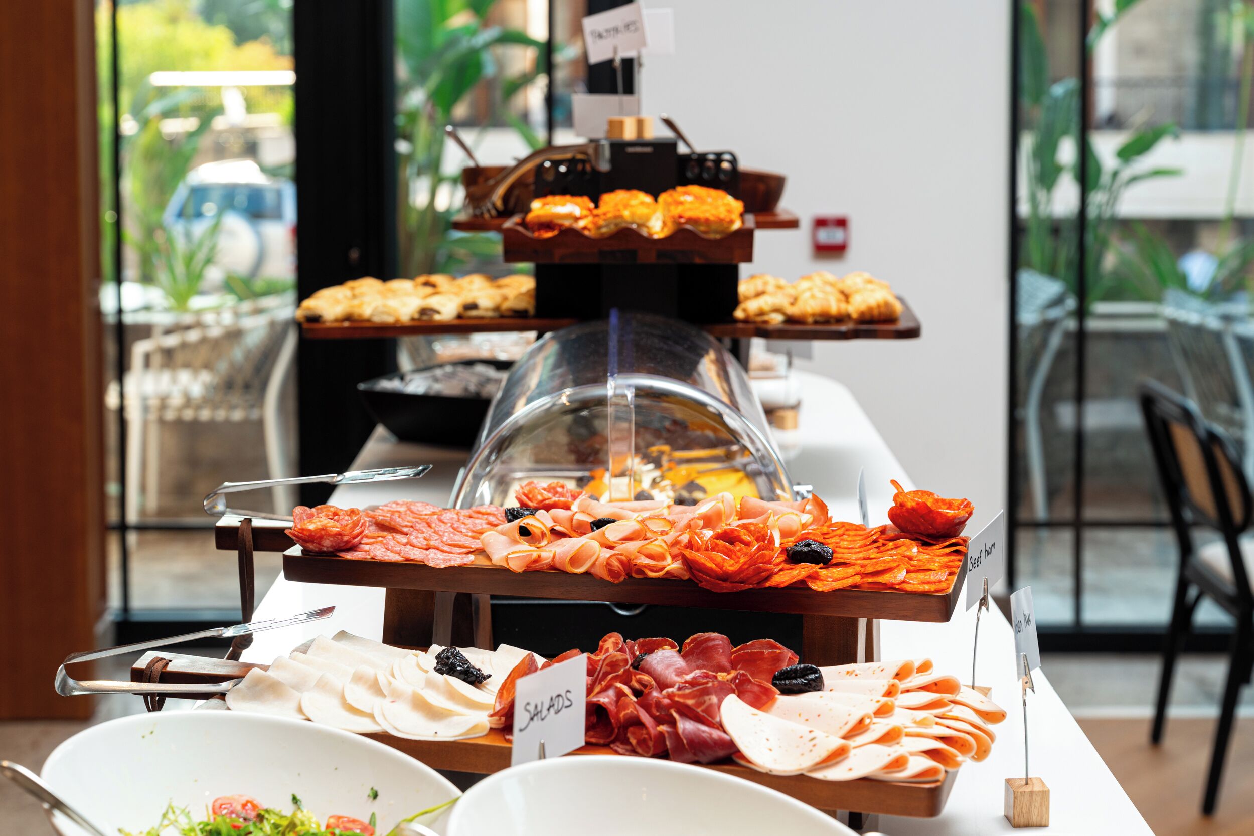 A buffet with various food items including meats, cheeses, and pastries.