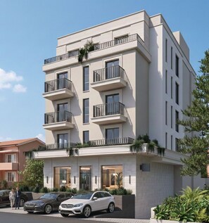 A multi-story residential building with balconies, a parking area, and a driveway. - Hotel Madeira (Budva)