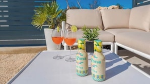 Pöydällä on kaksi Arizona Iced Tea -pulloa, kaksi lasia punaista juomaa ja pieni ruukkukasvi.
