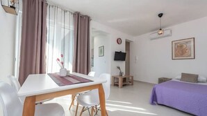 A modern room with a dining table, chairs, a bed, and a TV. - Villa Isola apartments 2 (Novalja)