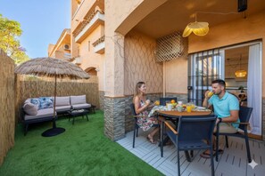 A patio with a sofa, a table with drinks, and a thatched umbrella. - Private Chill-out | NETFLIX| 8min Beach | Family (Vera)