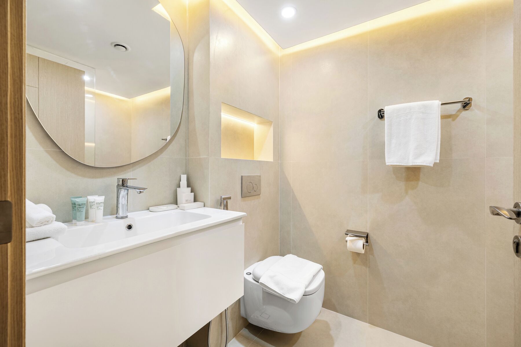 A modern bathroom with a white sink, mirror, and toilet.