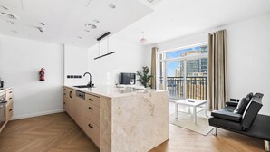 A modern apartment with a kitchen island, a dining area, and a living space with a black sofa. - Studio Near Dubai Mall Burj Khalifa (Dubai)
