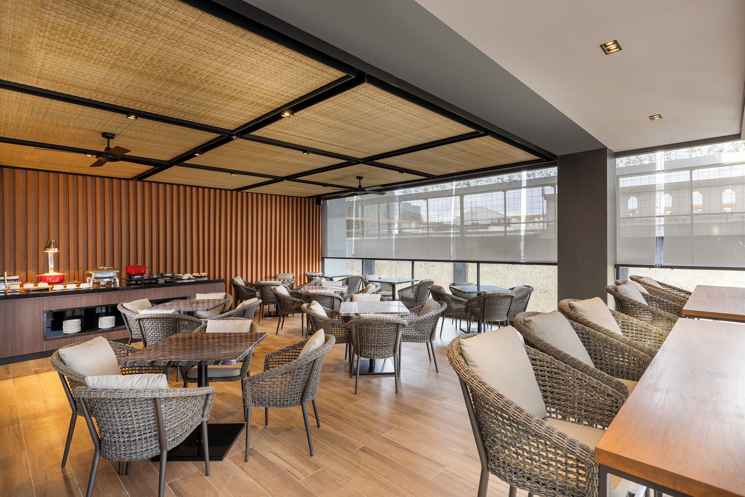 En modern restaurang med möbler i rotting, ett område med buffé och stora fönster.