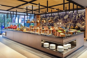 A buffet with various food items, a counter with plates, and a decorative wall with patterns.